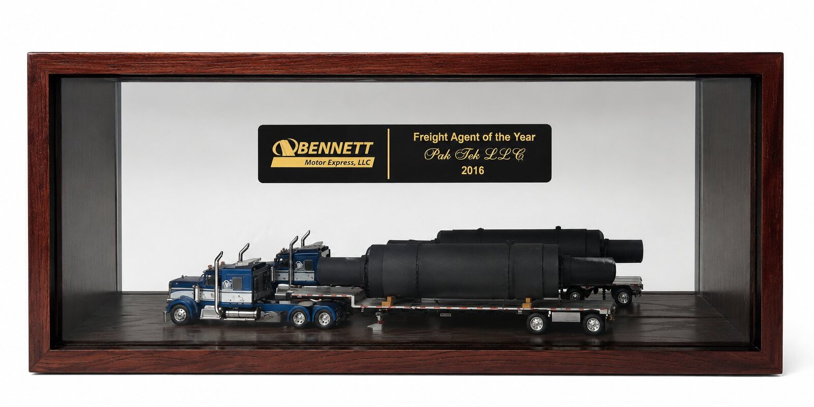 PakTek LLC's Bennett Motor Express Freight Agent of the Year 2016 award case, with a scale-model flatbed truck loaded with industrial cylinders beside a gold-lettered plaque